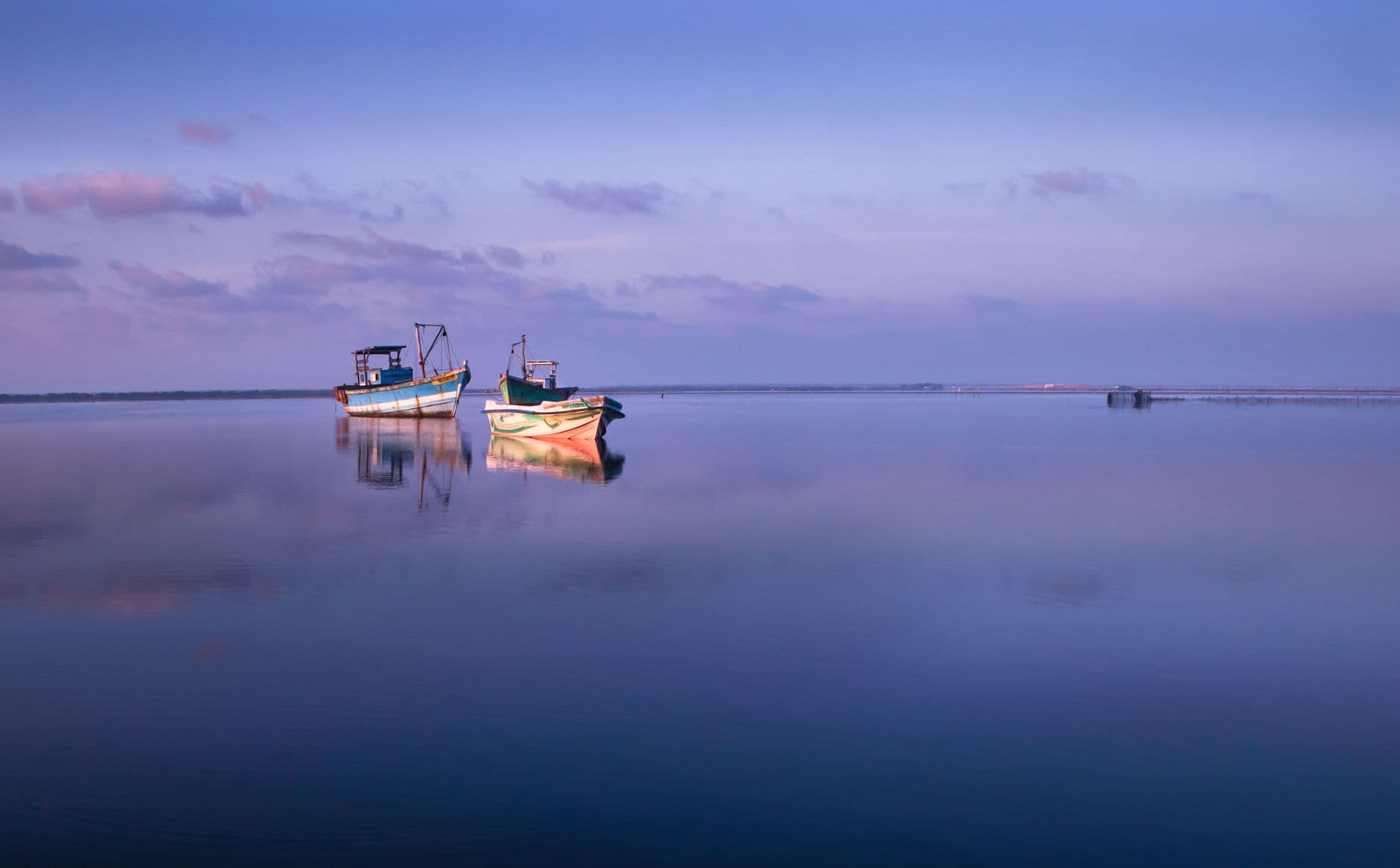 Fishing boats at rest on the glassy Jaffna lagoon at dusk
