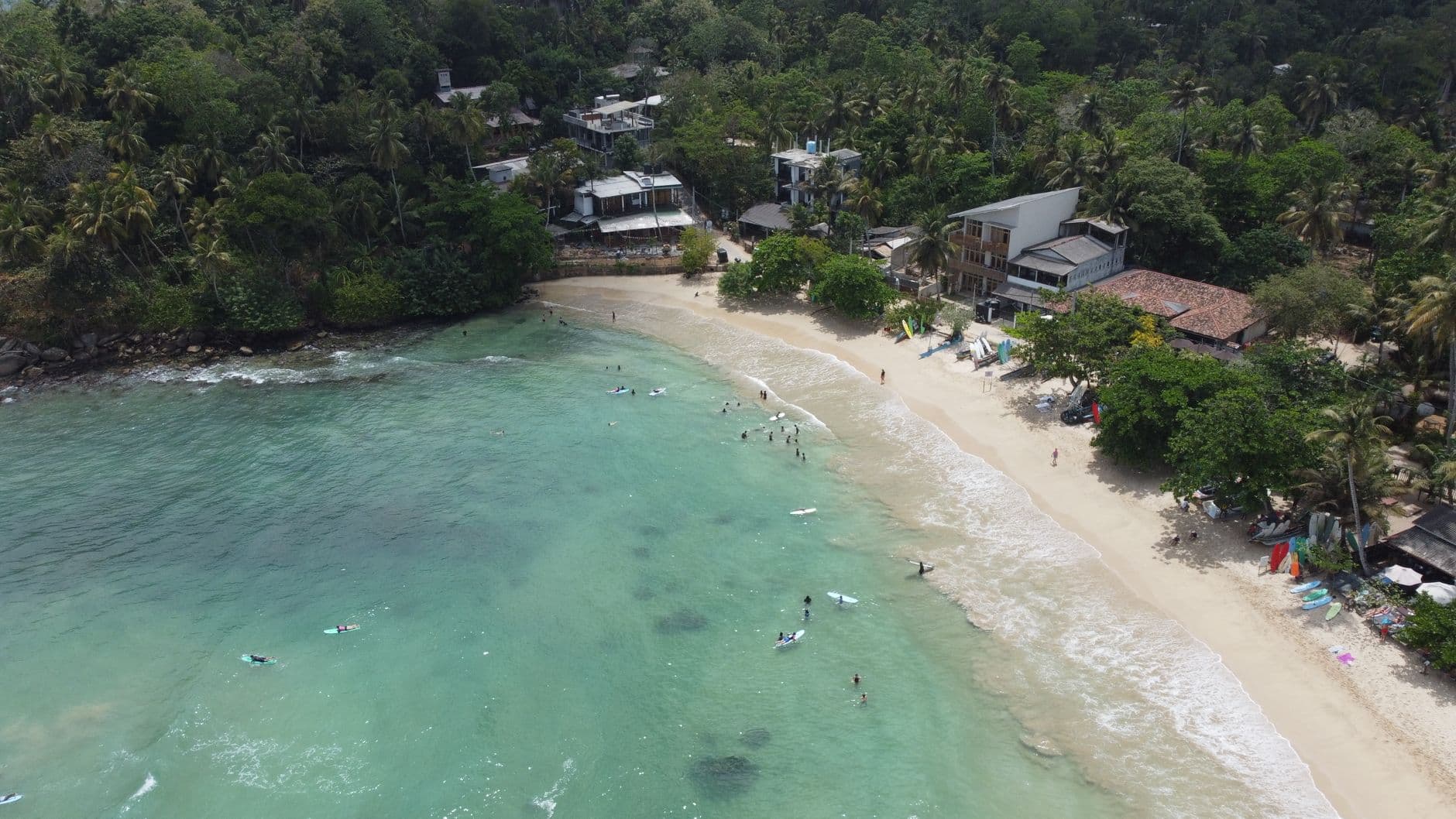 Surfers in the turquoise shallows of Hiriketiya Bay